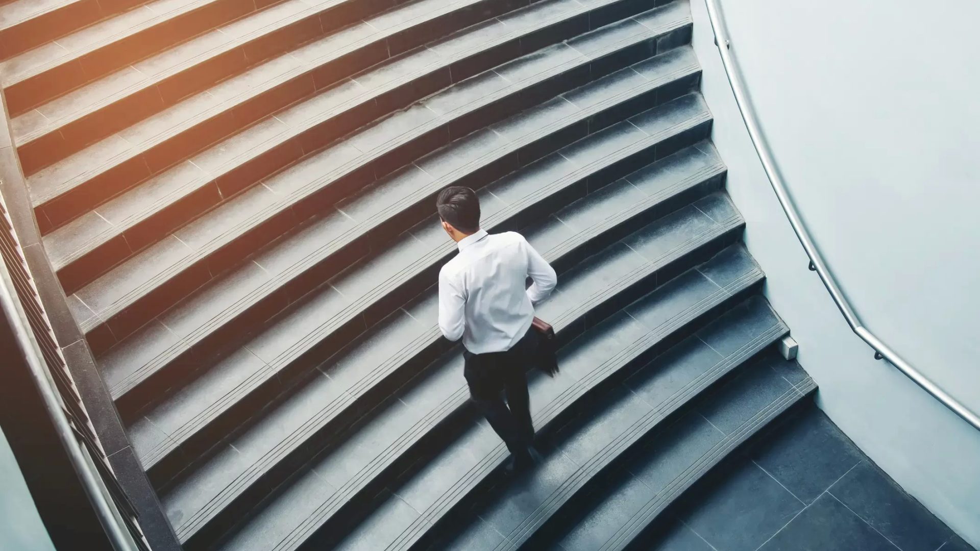 Geschaeftsmann steigt Treppe im Buerogebäude auf