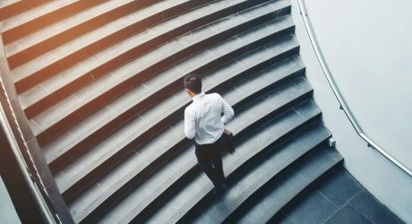 Geschaeftsmann steigt Treppe im Buerogebäude auf